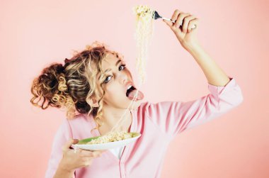 Bir tabak hazır şehriyeli seksi kız. Erişte yiyen güzel bir kız. Sabah kahvaltısı. Kıvırcık saçlı moda kadın çatallı İtalyan makarnası yiyor. Lezzetli İtalyan spagettisi yiyen kadın.