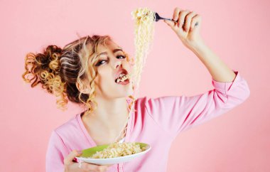 Erişte yiyen seksi kız. Hazır şehriyeli güzel bir kadın. Sabah kahvaltısı. Lezzetli İtalyan spagettisi yiyen bir kadın. Kıvırcık saçlı moda kız çatallı İtalyan makarnası yiyor.