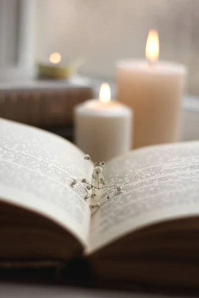 stock image Old books and candles. Cozy postcard. White flowers. Romantic photo. A simple winter decoration on the windowsill.