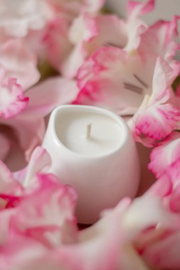 Yumuşak bir yüzeyde beyaz seramik mumlar ve arka planda bulanık pembe çiçekler. Rahatlama, sağIık, aromaterapi ve ev dekorasyonu için minimalist spa kompozisyonu.