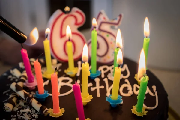 Lighting happy birthday cake candles. Chocolate cake 65th birthday party celebration