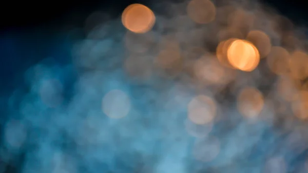 Blue and orange blurred lights pattern at night. Bokeh ball creative abstract background. Glittering city lights reflecting in water