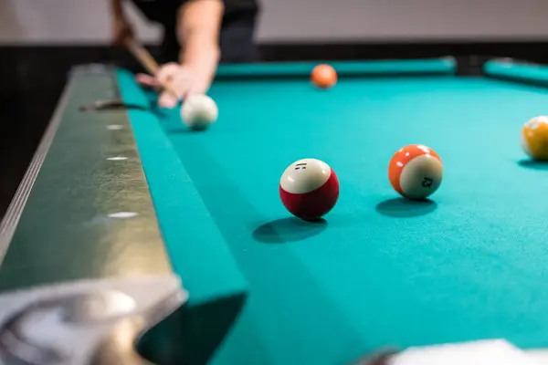 Pool table billiard game with shallow depth of field. Hand holding a pool cue taking a shot
