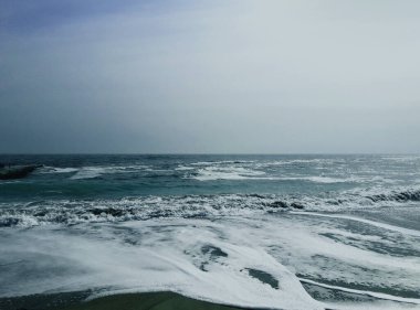 Beyaz köpüklü deniz dalgası sörfü. Deniz Burnu. Islak kum.