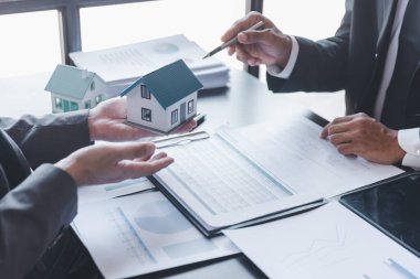 İş yeri, gayrimenkul ve yatırım kavramları. Emlakçı, emlak yatırımını tartışan müşteri ve yatırımcıya ev satın alma anlaşmasının şartlarını sundu