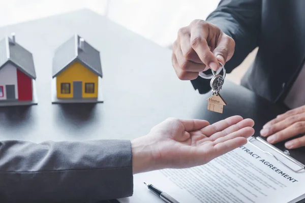 Home sales,home rental and real estate concept.Hands of estate agent giving keys to the Customer after sign the document while explain about the terms of the home purchase or rental agreement