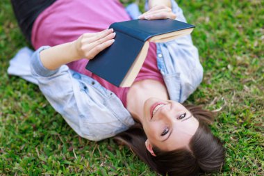 Beautiful young lady reading exciting story book in park, enjoying lazy morning, having relaxing weekend