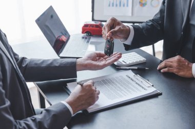 Concept of Car insurance or rental, salesman is making deal with buyer and giving key to him after sign sell contract or rental agreement.