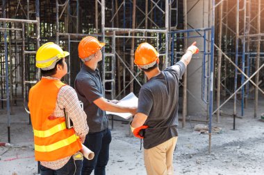 Concept of construction. Engineer, architect and designer working together at the construction site, Foreman or engineer checking the accuracy of the construction work by using blueprints..