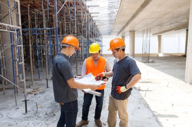 Concept of construction. Engineer, architect and designer working together at the construction site, Foreman or engineer checking the accuracy of the construction work by using blueprints..