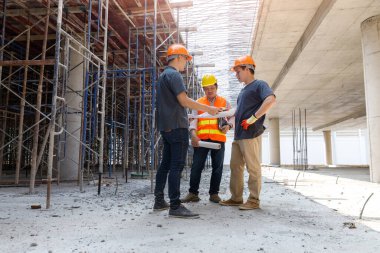 Concept of construction. Engineer, architect and designer working together at the construction site, Foreman or engineer checking the accuracy of the construction work by using blueprints..