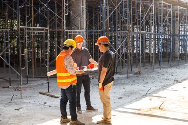 Concept of construction. Engineer, architect and designer working together at the construction site, Foreman or engineer checking the accuracy of the construction work by using blueprints..