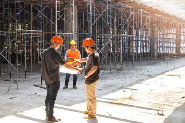 Concept of construction. Engineer, architect and designer working together at the construction site, Foreman or engineer checking the accuracy of the construction work by using blueprints..