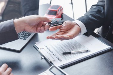 Concept of Car insurance or rental, salesman is making deal with buyer and giving key to him after sign sell contract or rental agreement.