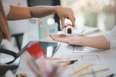 İnşaat ve mimarlık firması konsepti, mühendisler, mimarlar ve tasarımcılar birlikte çalışıyor, Mimarlar model evi inşaattan önce taslak ile birlikte inceleme için ellerinde tutuyorlar.