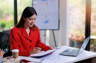 İş kadını çalışma konsepti, iş kadını çalışma masasında dizüstü bilgisayar kullanarak belge ve iş yatırımı grafik verilerini analiz ederek yatırım planı üzerinde çalışıyor..