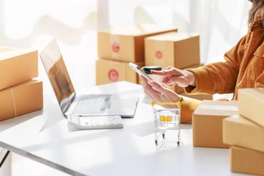 Concept of parcel delivery and selling online,Retailer Using a calculator to calculate sales for the day on an online store for pack into the parcel box and prepare to send the product to the customer