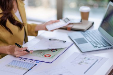 İş kadını çalışma kavramı, yakın plan iş kadını hesap makinesi ve dizüstü bilgisayar kullanarak belge ve iş yatırımı grafik verilerini analiz ederek yatırım planını kontrol ediyor
