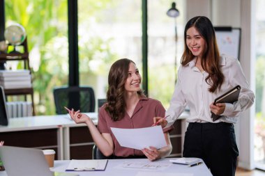 İş kadını, iş kadını, iş kadını, ortağıyla yatırım planı üzerinde çalışıyor ve hesap makinesi ve dizüstü bilgisayar kullanarak iş yatırım grafiği verilerini analiz ediyor.
