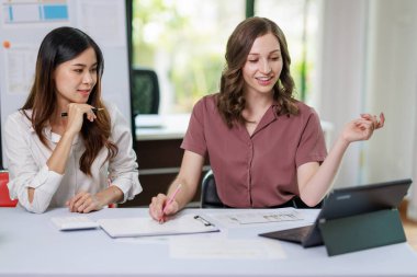 İş kadını, iş kadını, iş kadını, ortağıyla yatırım planı üzerinde çalışıyor ve hesap makinesi ve dizüstü bilgisayar kullanarak iş yatırım grafiği verilerini analiz ediyor.