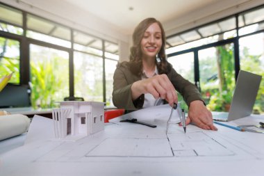 İnşaat konsepti: İnşaat Mimarı ve İnşaat Mimarı İnşaat Modeli ve Mimarı İnşaat Mimarı ama inşaat alanından önce bilgisayar dizüstü bilgisayar hesap makinesiyle inşaat planını tartışıyor