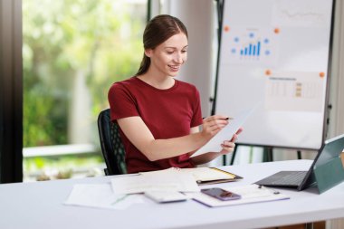 İş kadını çalışma kavramı, iş kadını gülümsemesi, iş yerindeki bilgisayarını kullanarak belge ve iş yatırımı grafik verilerini analiz ederek yatırım planı üzerinde çalışırken gülümsemesi..