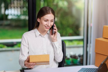 Concept of parcel delivery and selling online,Retailer Using a calculator to calculate sales for the day on an online store for pack into the parcel box and prepare to send the product to the customer