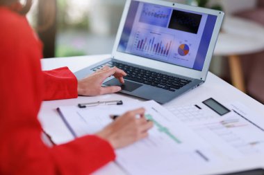 İş kadını çalışma kavramı, iş kadını gülümsemesi, iş yerindeki bilgisayarını kullanarak belge ve iş yatırımı grafik verilerini analiz ederek yatırım planı üzerinde çalışırken gülümsemesi..