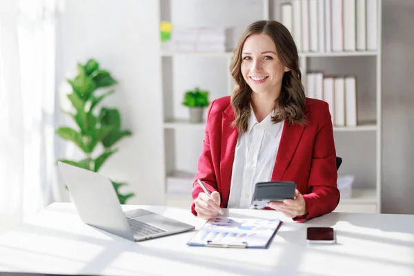 stock image Concept of business office woman working,Businesswoman smile while working about her invesment plan with analyzing document and business investment graph data by using laptop on desk in workstation.