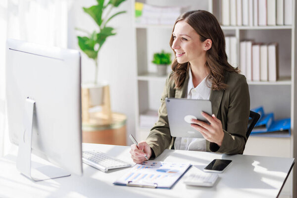 Concept of business office woman working,Businesswoman smile while working about her invesment plan with analyzing document and business investment graph data by using laptop on desk in workstation.
