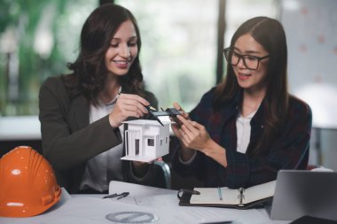 İnşaat konsepti: İnşaat Mimarı ve İnşaat Mimarı İnşaat Modeli ve Mimarı İnşaat Mimarı ama inşaat alanından önce bilgisayar dizüstü bilgisayar hesap makinesiyle inşaat planını tartışıyor