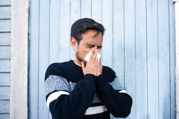 Man with allergy blowing his nose