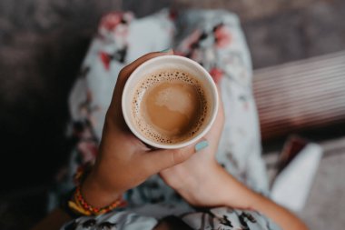 Bir kadının ellerinde dumanı tüten bir fincan kahve.