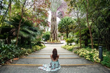 Singapur körfezi yakınlarındaki Gardens girişine bakan bir turist oturuyor..