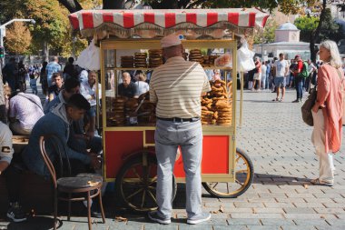 İstanbul, Türkiye - Ekim 12022: Sultanahmet 'in turizm ilçesindeki geleneksel bir Türk sokak satıcısı İstanbul, Türkiye' deki bir gıda standında simit satıyor.