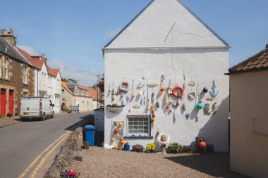 Lower Largo, İngiltere - 9 Haziran 2023: Denizcilik temalı balıkçılık malzemeleri, deniz kenarındaki Lower Largo, Fife, İskoçya, İngiltere 'de bulunan sahil balıkçı köyünde bulunan beyaz yıkamalı çakıl taşlı duvar üzerindeki deniz ürünleri ve dekorasyon.