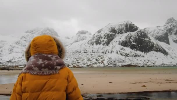 在挪威的罗浮敦岛上 穿着普弗夹克的女士冬季在雪山上张望 — 图库视频影像