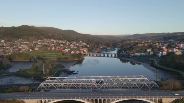 日の出にスペインのガリシア ポンテベドラのアーケード街の横にあるVerdugo川のSampaioと呼ばれる金属製の橋の上で撮影された空中ドローン転送 — ストック動画