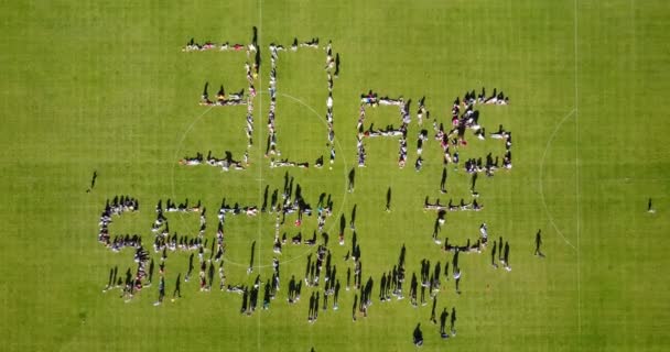 Crowd Spelling Out Letters Using Human Bodies Aerial Drone — Stock Video
