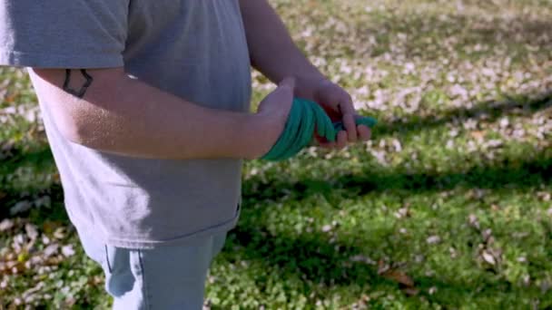 在拍摄过程中 人物形象在后院从他的手上拉开绿色绷带 慢动作 — 图库视频影像