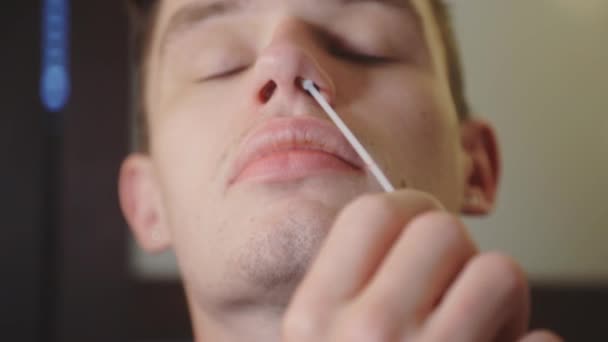 男子旋转消毒鼻腔周围的鼻孔 Covid 19测试套件在家里 — 图库视频影像