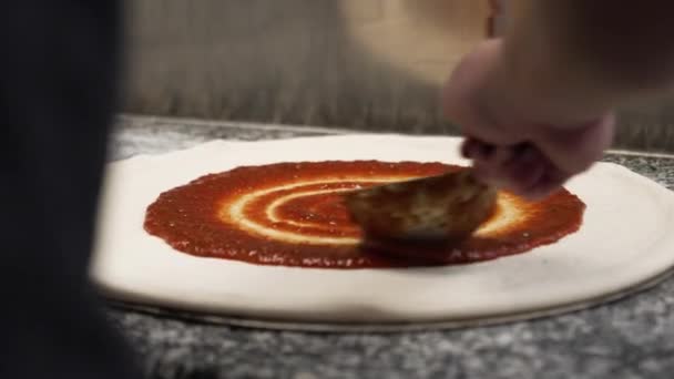 Pizzabäcker Verteilt Rote Sauce Gleichmäßig Uhrzeigersinn Über Rohen Pizzateig Zeitlupe — Stockvideo