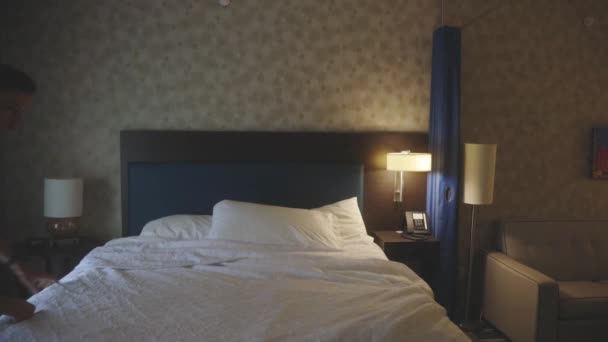 若い男は毛布を固定し 彼のホテルの部屋に枕 — ストック動画