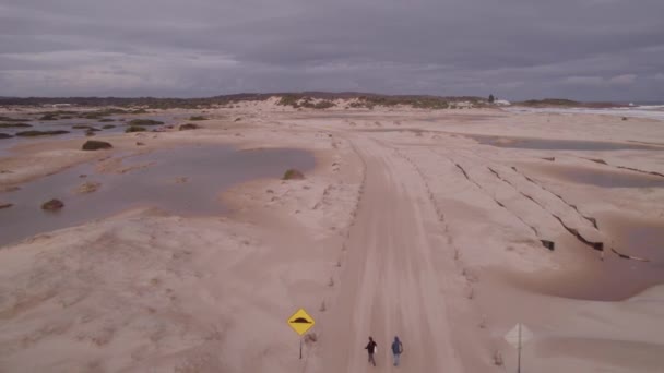 ニューサウスウェールズ州のハンター地域でストックトンビーチの近くのサンディトレイルを歩く人々 オーストラリア ドローン プルバック — ストック動画