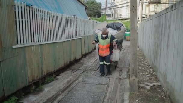 Staruszek Masce Ciągnący Wózek Załadowany Plastikowymi Śmieciami Wąskiej Ulicy Bangkoku — Wideo stockowe