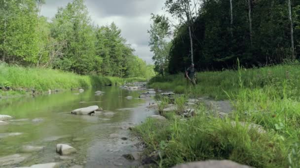 Caminhante Usando Mochila Explora Exuberante Margem Rio Dia Nublado Verão — Vídeo de Stock
