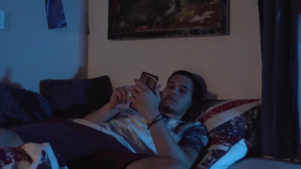 Sıkılmış Bir Adam Yatakta Yatarken Akıllı Telefonuna Bakıyor — Stok video