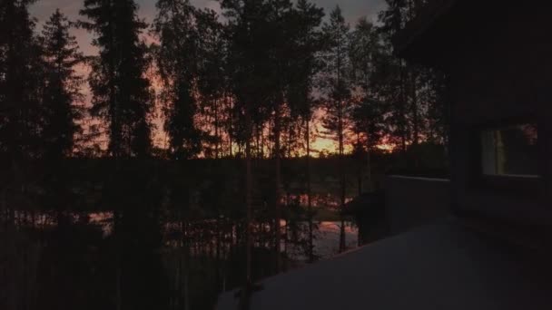 美しい穏やかな湖とキャビンで木の上を飛行する広い角度の空中ショット日没時 — ストック動画