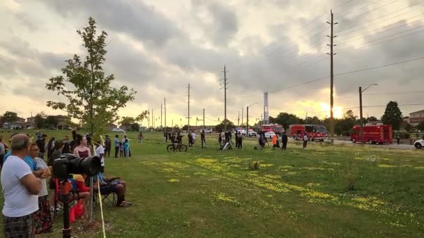 People Watching Grass Field Crime Scene Firefighters Vehicles Parked Road — Stock Video