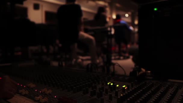 バックグラウンドで演奏する音楽家の視点で録音スタジオでのミキシングパネルの閉鎖 — ストック動画